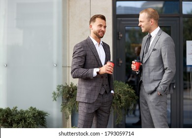 Two Business People Take A Break, They Stand Talking Outdoors, Holding Cup Of Coffee. Business People, Cooperation, Co-working Concept