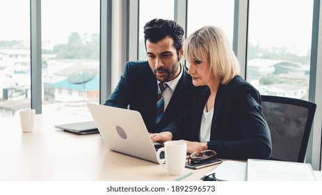 Two Business People Talk Project Strategy At Office Meeting Room. Businessman Discuss Project Planning With Colleague At Modern Workplace While Having Conversation And Advice On Financial Data Report.