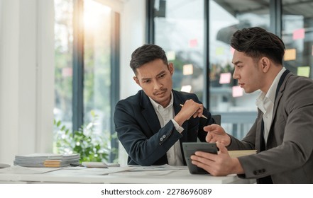 Two business people talk project strategy at office meeting room. Businessman discuss project planning with colleague at modern workplace while having conversation and advice on financial data report. - Shutterstock ID 2278696089