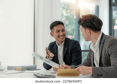 Two business people talk project strategy at office meeting room. Businessman discuss project planning with colleague at modern workplace while having conversation and advice on financial data report. - Shutterstock ID 2278696091