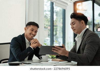 Two business people talk project strategy at office meeting room. Businessman discuss project planning with colleague at modern workplace while having conversation and advice on financial data report. - Shutterstock ID 2278696095