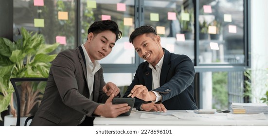 Two business people talk project strategy at office meeting room. Businessman discuss project planning with colleague at modern workplace while having conversation and advice on financial data report. - Shutterstock ID 2278696101