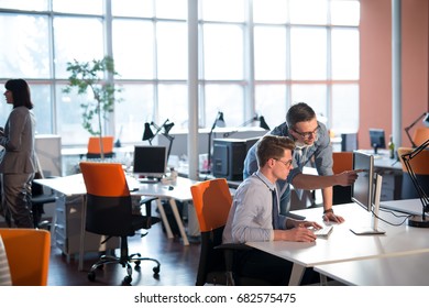 zwei Geschäftsleute, die Computer für das nächste Treffen vorbereiten und Ideen mit Kollegen im Hintergrund diskutieren