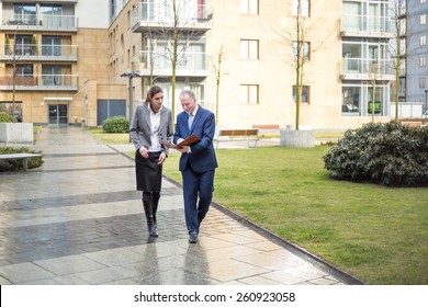 Two Business People Walking And Discussing Outside The Office