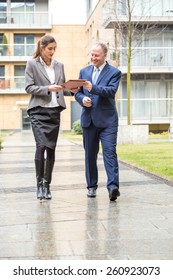 Two Business People Walking And Discussing Outside The Office