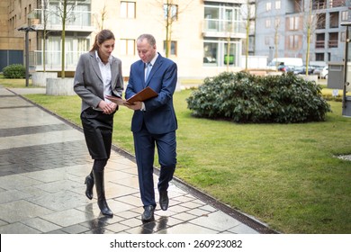 Two Business People Walking And Discussing Outside The Office