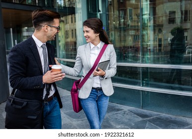 Two Business People Walking Outside In Front Of Modern Business Building.