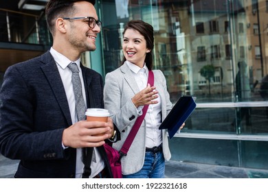 Two Business People Walking Outside In Front Of Modern Business Building.