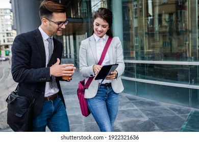 Two Business People Walking Outside In Front Of Modern Business Building.