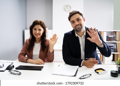 Two Business People Waving Hello To Webcam In Video Conference