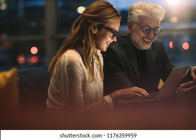 Two Business Professionals Working Late Together In Office. Business People Working On A Project.