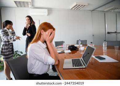 Two business women bully a colleague in the workplace, sad woman feels excluded. - Powered by Shutterstock