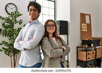 Two business workers smiling happy with arms crossed gesture at the office.