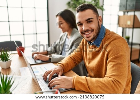 Two business workers smiling happy working sitting on desk at the office.