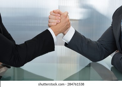Two Businessman Holding Each Other Hands Over Desk In The Office