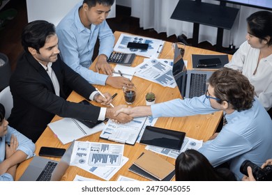 Two businessman shake hand in meeting room with coworker give cheerful applause. Team of analyst celebrate after successful significant progress on business strategic performance. Meticulous - Powered by Shutterstock