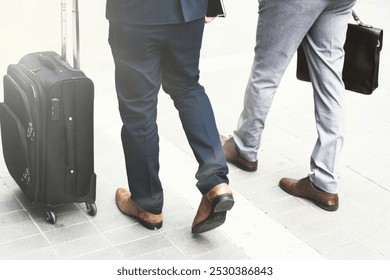 Two businessmen in business attire walk with luggage and briefcase. Urban business travel scene. Businessmen going on business trip. Business people walking with luggage together. - Powered by Shutterstock