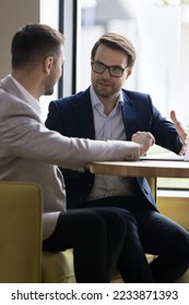 Two businessmen discuss cooperation meet in company office, talking seated at table, express opinion, share ideas and thoughts, solving common business, vertical image. Negotiations between partners - Shutterstock ID 2233871393