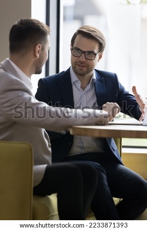 Two businessmen discuss cooperation meet in company office, talking seated at table, express opinion, share ideas and thoughts, solving common business, vertical image. Negotiations between partners Foto stock © 