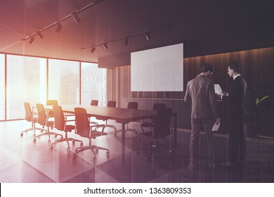 Two businessmen discussing documents in stylish wooden conference room with long black table and white projection screen. Toned image double exposure