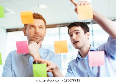 Two businessmen discussing ideas written on sticky notes