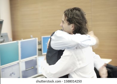 Two Businessmen Hugging In Office