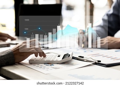 Two businessmen are meeting together, they point to financial documents to discuss plans and solutions, chart graphics showing financial status and performance. Business administration concept. - Shutterstock ID 2122327142