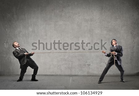 Two businessmen playing tug of war
