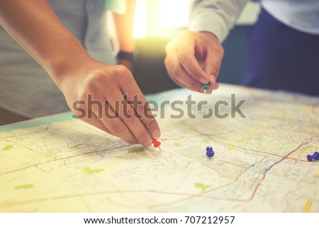 Two businessmen is pointing at the map with the pins in business meeting. They are brainstorming about the target of customer in terms of marketing.