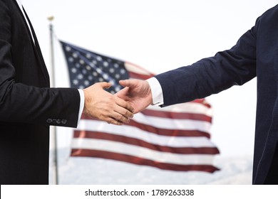 Two businessmen shake hands on the background of USA flag, partnership concept, close up - Powered by Shutterstock
