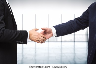 Two businessmen shake hands in a sunny empty office, close up - Shutterstock ID 1628326990
