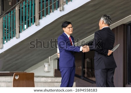 Two businessmen shake hands while one hides a knife behind his back, symbolizing betrayal, deceit, backstabbing, and the dangers of trust and dishonesty in business relationships.