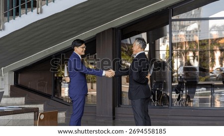 Two businessmen shake hands while one hides a knife behind his back, symbolizing betrayal, deceit, backstabbing, and the dangers of trust and dishonesty in business relationships.
