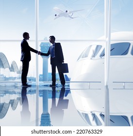 Two Businessmen Shaking Hands In An Airport.