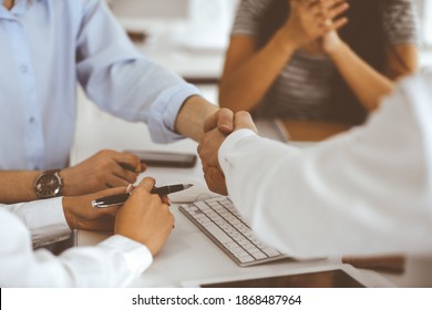 Two businessmen are shaking hands in office while sitting at the desk, close-up. Colleagues applauding of success meeting end. Business people concept - Shutterstock ID 1868487964
