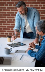 two businessmen using tablet computer discussing financial graph data on mobile touchscreen device in meeting