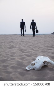 Two Businessmen Walking Away From An Animal Skull In The Desert