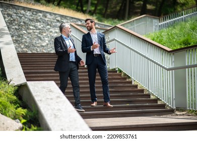 Two Businessmen Walking Down The Stairs And Talking