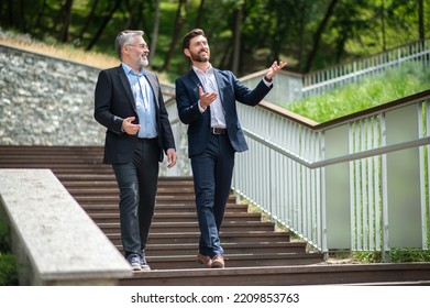 Two Businessmen Walking Down The Stairs And Talking