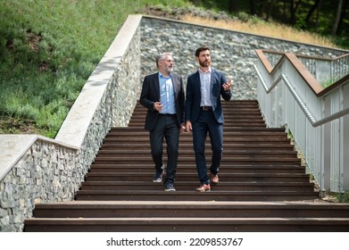 Two Businessmen Walking Down The Stairs And Talking