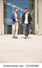 Two Businessmen Walking And Talking Outdoors