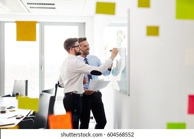 Two Businessmen Working At Office Planning New Strategy On Whiteboard