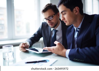 Two Businessmen Working With Touchpad At Meeting In Office