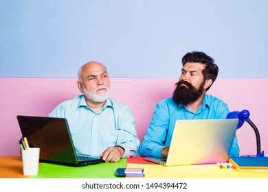 Two Businessmen Working At Workplace. Businessmen Using Laptop At Work. Two Different Generations Ages Sitting At Desk With Laptops