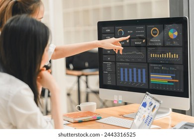 Two businesspeople or an accountant team are analyzing data charts, graphs, and a dashboard on a laptop screen in order to prepare a statistical report and discuss financial data in an office - Powered by Shutterstock