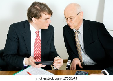 Two Businesspeople Crunching The Numbers, The Senior Guy Looking Sceptical