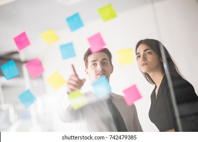 Two businesspeople discussing and planning concept. Front of glass wall marker and stickers. - Shutterstock ID 742479385