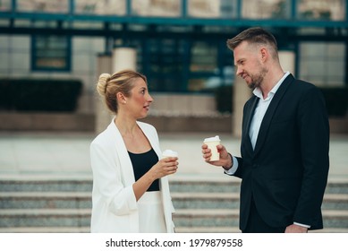 Two Businesspeople Drinking Coffee Takeaway Outside Of The Office While Having A Break On The Work