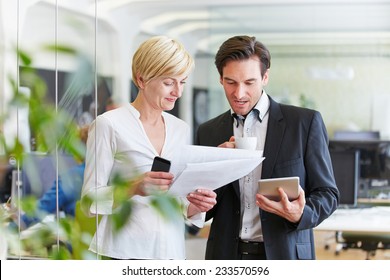 Two Businesspeople With Files Making Decisions In Office