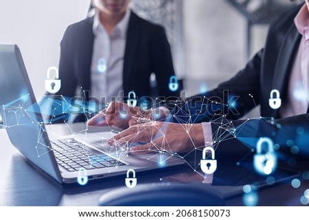 Two businesspeople in formal wear working on the project to protect cyber security of international company using laptop. Padlock Hologram icons. Teamwork concept.